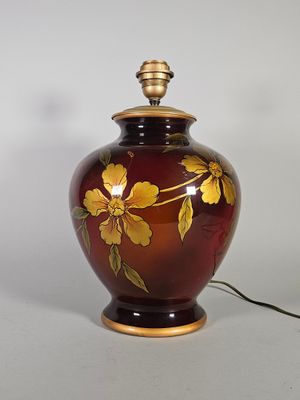 un vase rouge orné de fleurs jaunes, posé sur une table