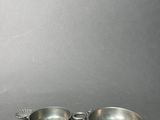pair of silver plated bowls and spoons on a gray surface