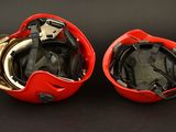pair of red helmets with gold accents on a black background