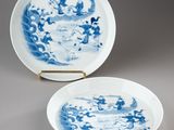 two blue and white plates with designs on them sitting on a table