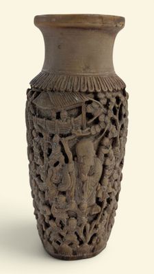 un vase marron orné de sculptures sur un fond blanc