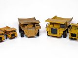 cinq camions miniatures alignés les uns à côté des autres sur une surface blanche
