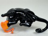 a black cat that is holding a orange object in it ' s mouth