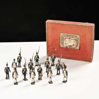 de nombreux petits soldats alignés devant une boîte rouge