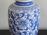 un vase bleu et blanc posé sur une table sur laquelle se trouve une lampe