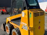 a picture of a yellow skid steer loader parked in a parking lot