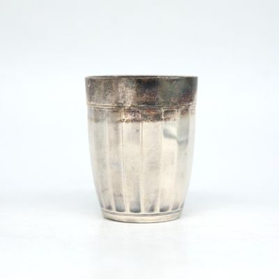 une tasse en argent posée sur une surface blanche