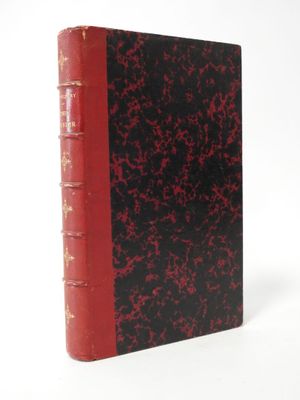 an old red and black book sitting on top of a white surface