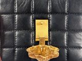 someone is holding a black purse with a gold buckle