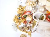 a pile of jewelry on a table with a bottle of perfume