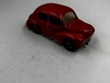 une petite voiture rouge posée sur une surface blanche
