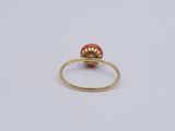 an image of a gold ring with a red bead
