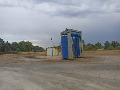 des toilettes bleues posées au milieu d'un champ de terre battue
