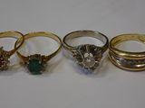 three gold rings with diamonds and emeralds on a white surface