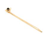 the gold and black stone hair pin is laying on a white surface