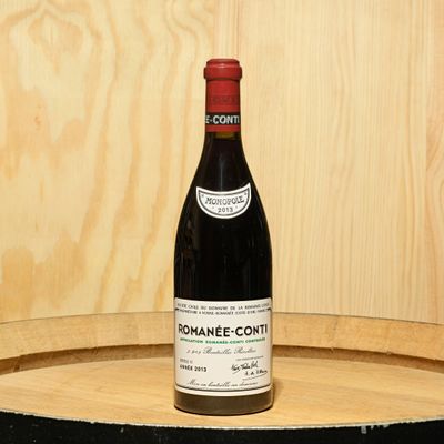 a bottle of wine sitting on top of a barrel