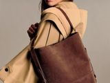 La femme porte un sac marron et un manteau beige.