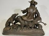 bronze statue of a man with a dog and a bird on a rock