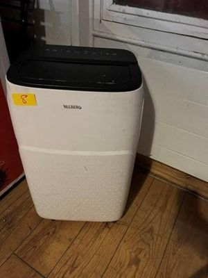 un purificateur d'air blanc posé au sol près d'une fenêtre
