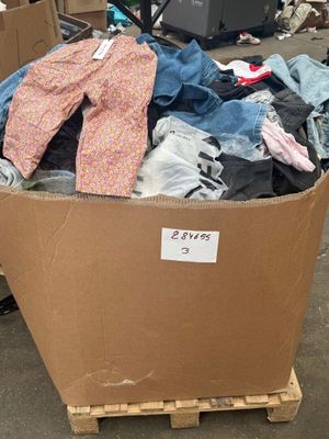 un carton rempli de vêtements et d'autres objets posé sur une palette