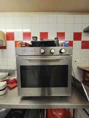 a stainless steel oven in a kitchen with red and white checkered walls