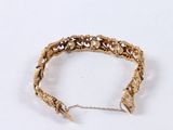gold bracelet with spikes and chains on a white surface