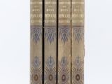 trois vieux livres sont empilés sur une surface blanche