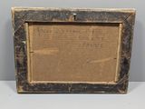 an old picture frame with writing on it sitting on a table