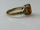 a gold ring with an orange stone in it
