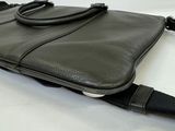 black leather laptop bag on a white surface with a black strap