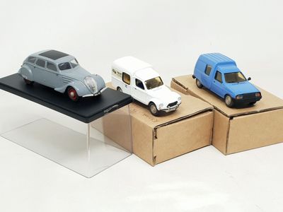 three small toy cars sitting on top of a cardboard box