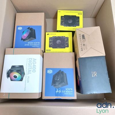 Plusieurs cartons contenant du matériel informatique sont empilés les uns sur les autres.