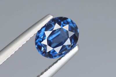 un gros plan d'un saphir bleu tenu par une paire de pinces