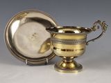 une coupe en argent et une assiette en argent posées sur une table