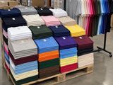 de nombreux t-shirts de différentes couleurs empilés sur une palette dans un magasin