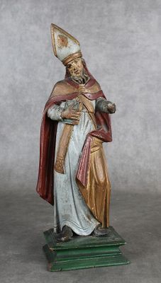 figurine représentant un homme vêtu d'une aube et tenant un livre
