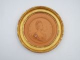 an old picture of a woman in a gold frame on a white wall