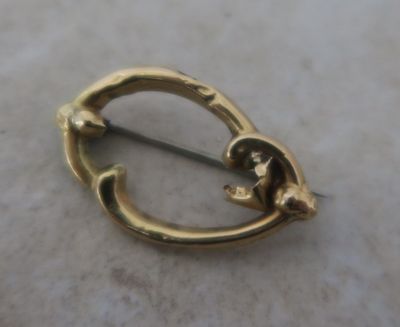 a small gold brooch on a marble surface