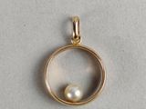 a gold pendant with a pearl inside of it
