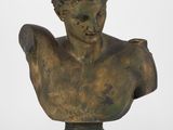 un buste antique en bronze représentant un homme aux cheveux bouclés, posé sur un socle