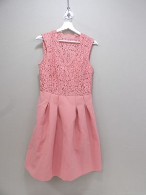 a pink dress hanging on a hanger against a wall