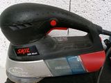a black and red sander sitting on top of a black bag