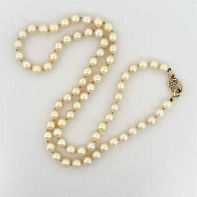 a close up of a pearl necklace on a white surface