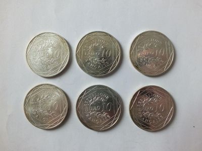 six different coins are shown in a row on a white surface