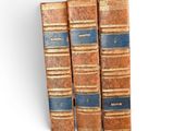 three old books sitting on top of each other on a shelf