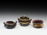 trois petits pots munis d'anses sont posés sur une table