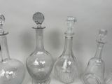 five glass bottles and a glass stopper on a white surface