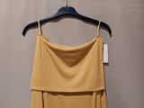 yellow dress hanging on a hanger in front of a gray wall