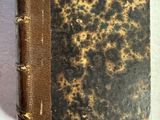 un vieux livre posé sur une table à côté d'un mur blanc