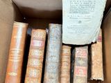 many old books in a cardboard box on the floor